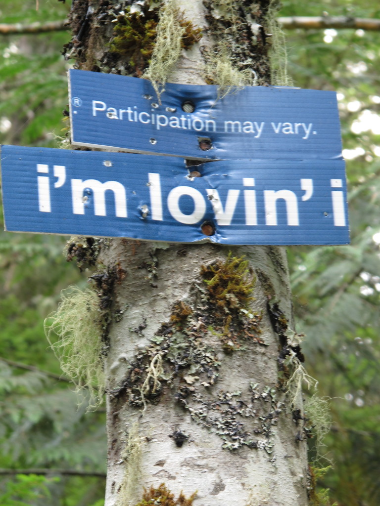 Signs nailed to a tree: "Participation may vary" and "I'm lovin' it"